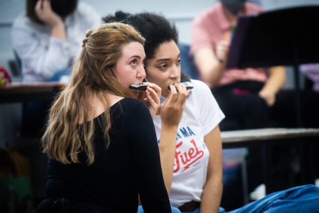 Danielle Pribyl (left) (CFA’22) and Alexis Peart (CFA’23) in a scene from Proving Up; both women blow on harmonicas and look off into the distance.