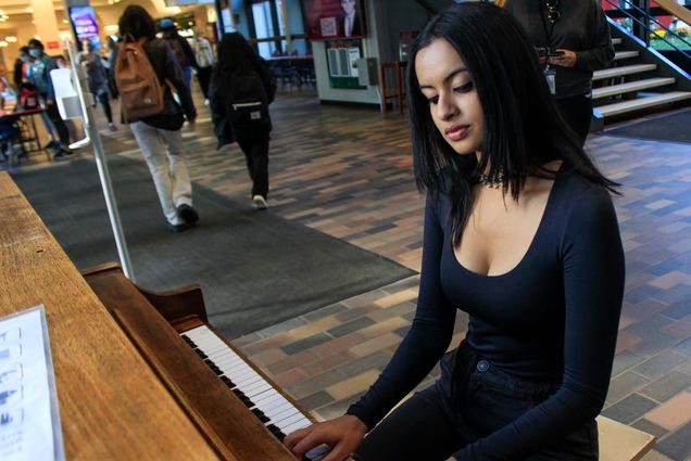 Photo of Musician Radha Rai (QST '21) playing piano at the GSU after undergoing a series of interviews regarding her encounter with famous singer John Legand the day prior. She wears a black top and pants, and looks contently at the piano as she plays.