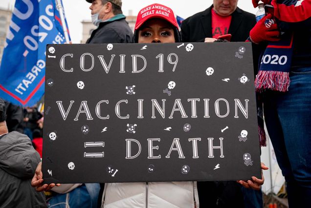 A protester holds a sign that says 'COVID 19 Vaccination = Death'