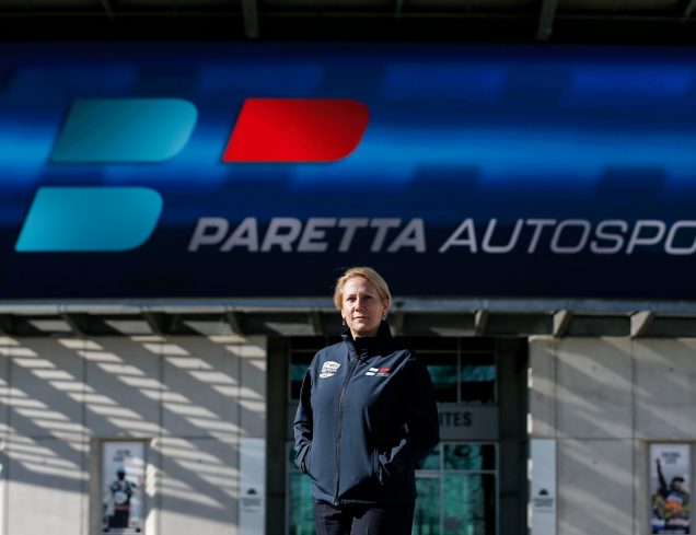 Paretta Autosport founder and CEO Beth Paretta standing in front of the Paretta Autosport pagoda with the Paretta Autosport sign in the background.