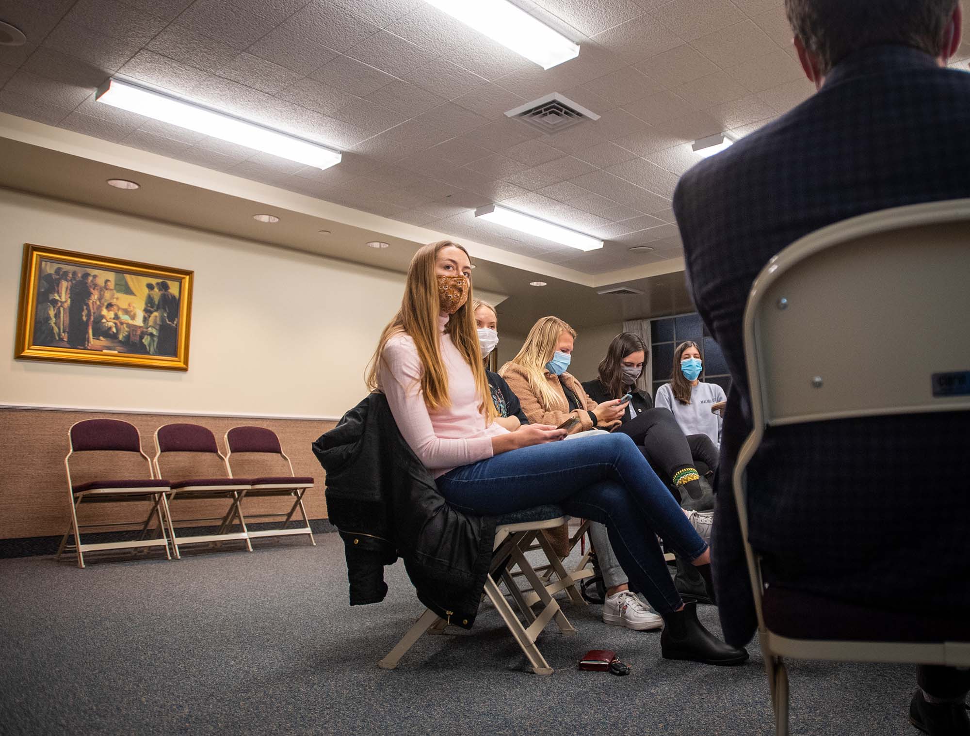 Photo of Caitlyn Wise (SAR’23), a young white white woman with long blonde hair, sitting in a chair amidst a circle of chairs all facing the center.