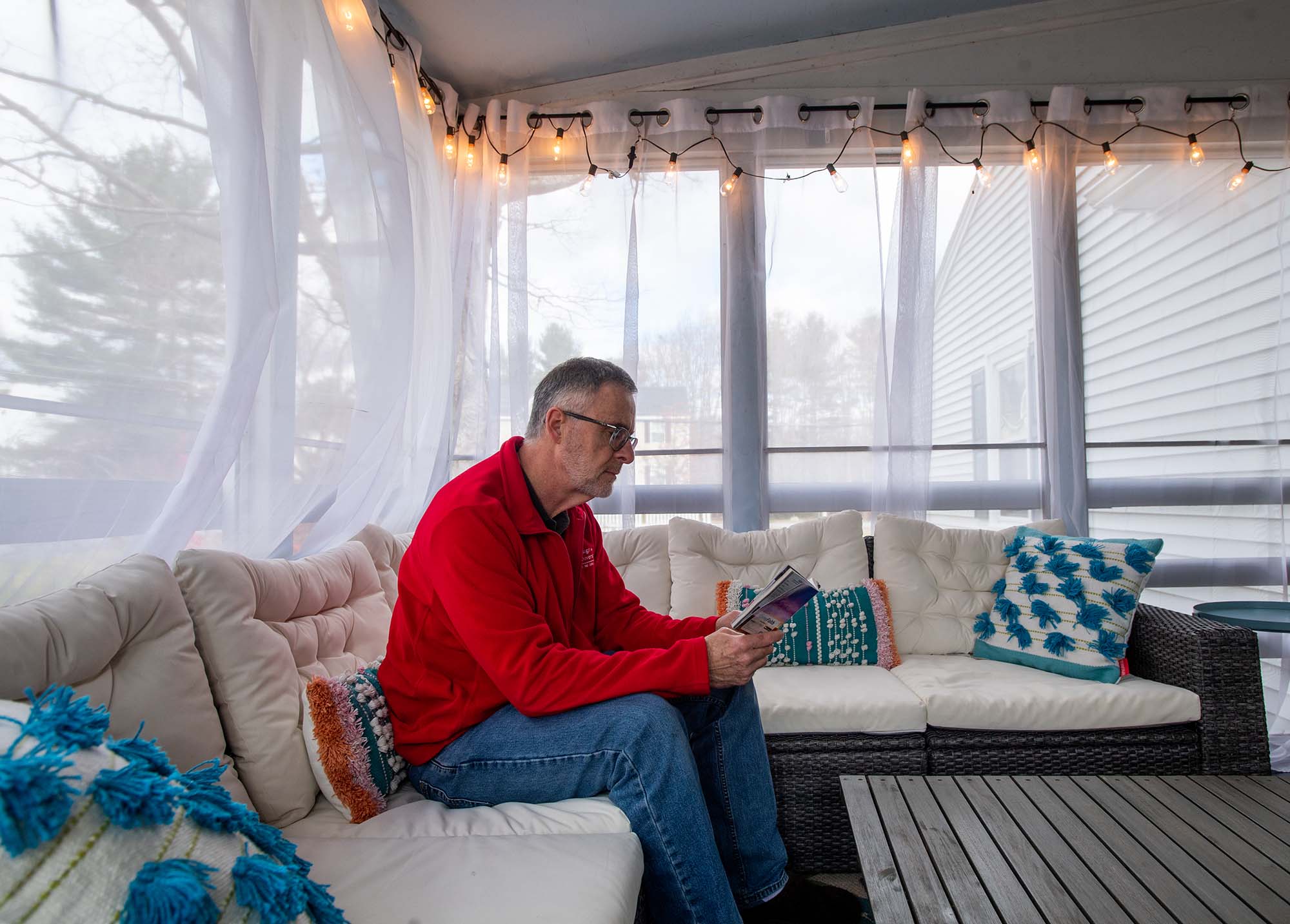 Photo of Ray Joyce, a white man with gray hair and black glasses, reading a daily devotional in his West Acton home.