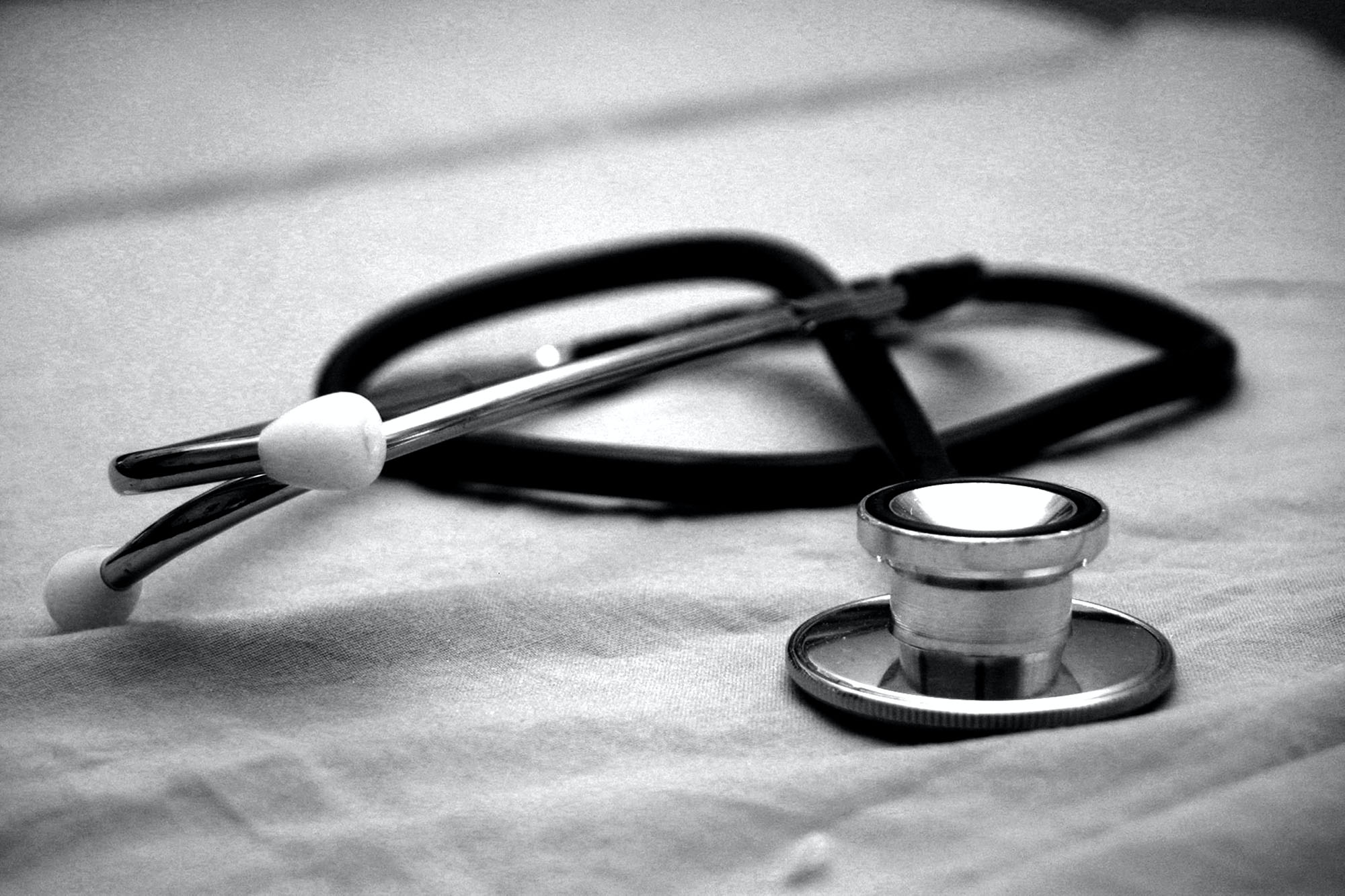 Black and white photo of a stethoscope laying on a linen cloth.