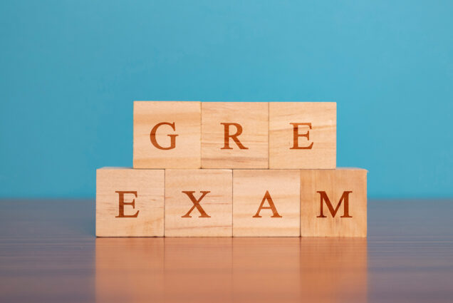 Image: Photo of toy wooden blocks with letters on them stacked on a table. The blocks spell " GRE Exam".