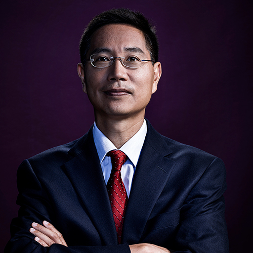 Photo of Christopher Chen. An Asian man wearing glasses and a navy suit poses with arms crossed in front of a dark purple backdrop.