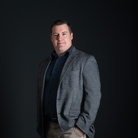 a photo of SPH assistant professor Kevin Lane as he poses in front of a black backdrop