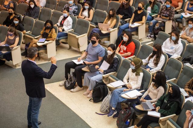 Photo of Uwe Beffert’s cell biology class September 2, 2021 in Morse Auditorium. Mask are required indoors, but distancing is not. Students sit in the rows with their notebooks open and look towards Beffert who wears a black jacket and jeans.
