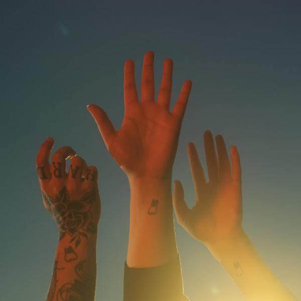 Album cover of "the record" by boygenius. cover shows three hands reaching for a blue sky as a faded, golden light shines on them./