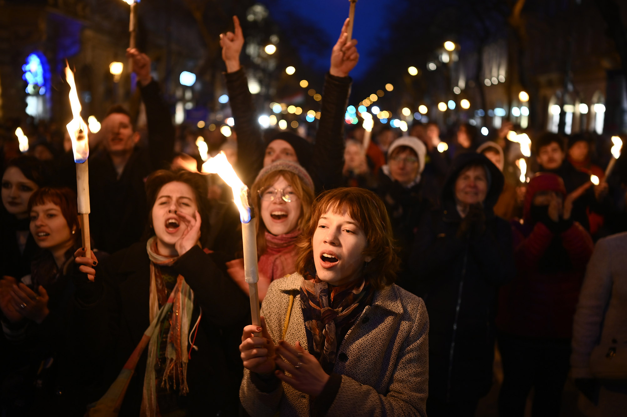 Photo: People hold torches and shouts slogans during a march, marking the 175th anniversary of a failed 1848 uprising, in Budapest, Hungary. the corwd is shown lit mainly by candles and streetlights during the nighttime march.
