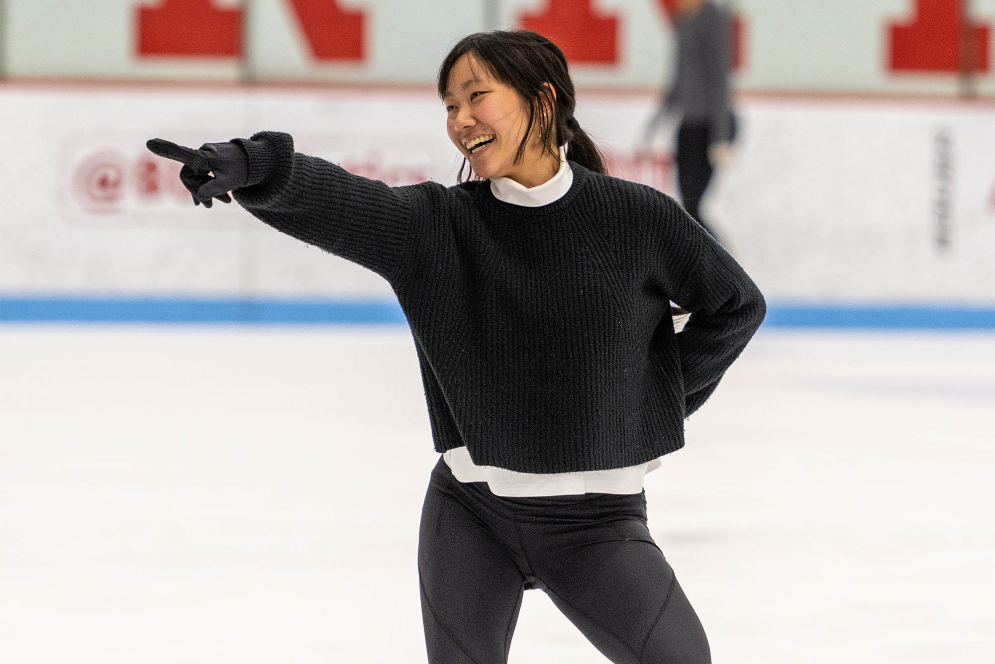 Photo: A member of the BU Figure Skating Club wearing black leggings and a black shirt points toward the stands while doing a routine in skates at Agganis Arena