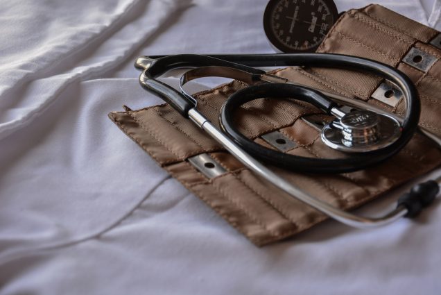 Photo: Close up photo of a black stethoscope lying on an open, brown carrying case. They both lie on white fabric