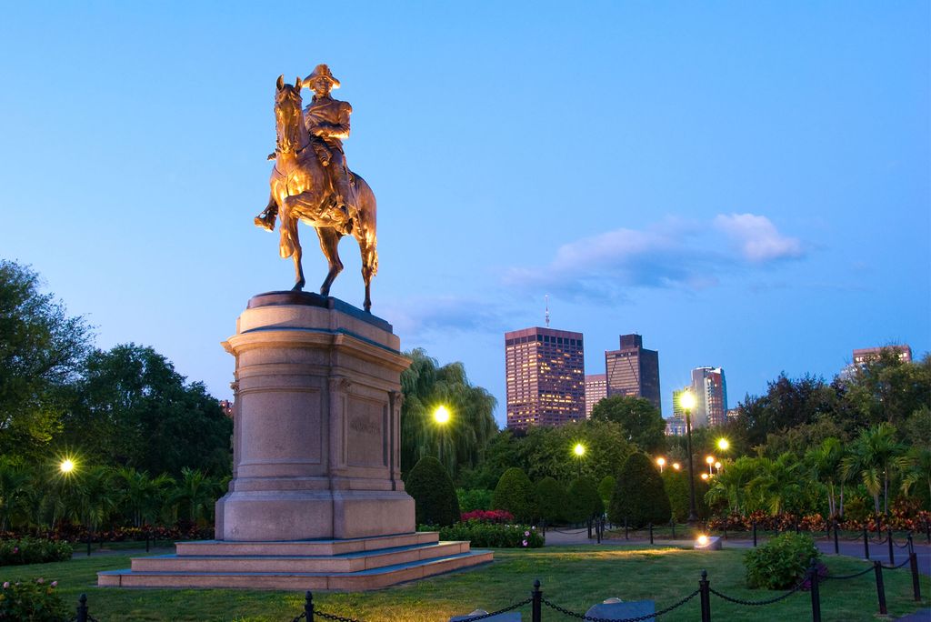 Photo: The George Washington statue at the Public Garden in Boston, MA at nighttime with office buildings in the distance.