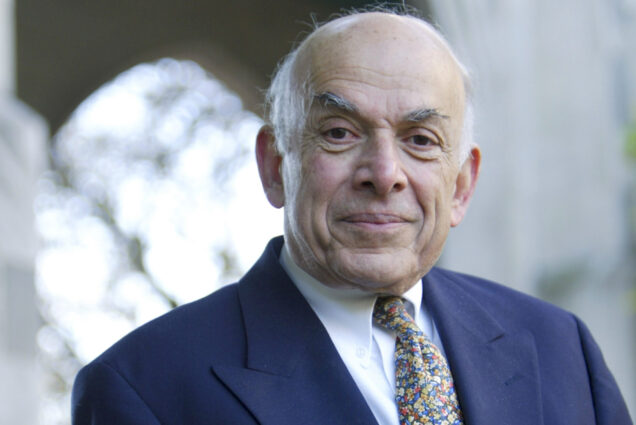 Photo: Portrait of Aram V. Chobanian standing outside Marsh Chapel on the B.U. campus. An older man balding man with white hair and wearing a white collared shirt, paisley tie, and navy suit, smiles and looks at the camera.