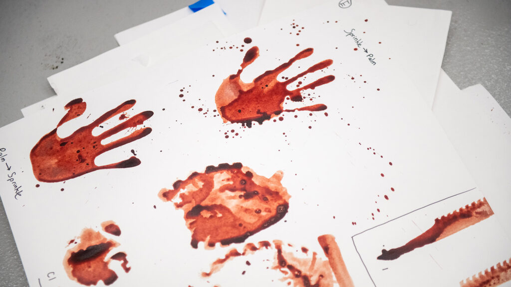 Photo: A paper showing various blood-like handprints and splatters is shown.