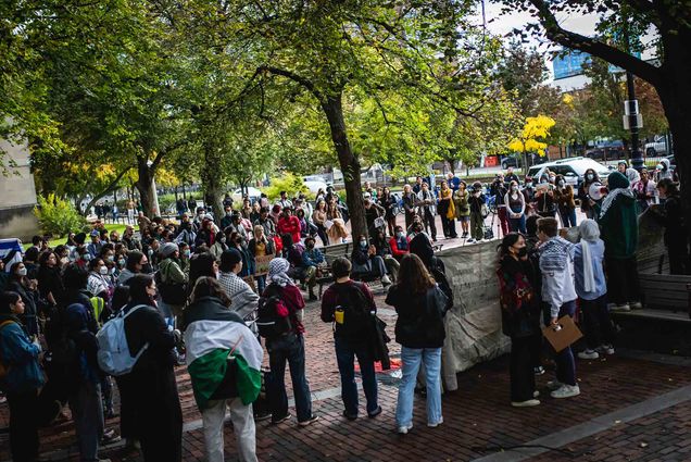 Photo: Students gather outside of the GSU during a walkout in support of Palestine on October 23, 2023. A crowd of students, some holding signs and and flags in support of Palestine, stand together on a cobblestone sidewalk area.