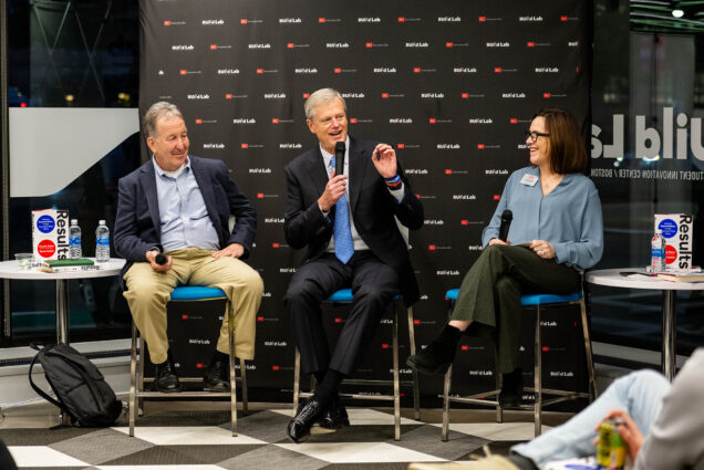 Photo: Former Massachusetts Governor Charlie Baker, center, and his former Chief of Staff Steve Kadish, at left, discuss their book Results: Getting Beyond Politics to Get Important Work Done during a panel discussion at Innovate at BU at the BUildLab November 2. Moderating was Innovate@BU Executive Director Siobhan Dullea (CAS'91), at right. Three people sit in chairs at the front of a room with a small seated audience. They hold and speak into microphones in front of a black background with the BU Build lab logo.