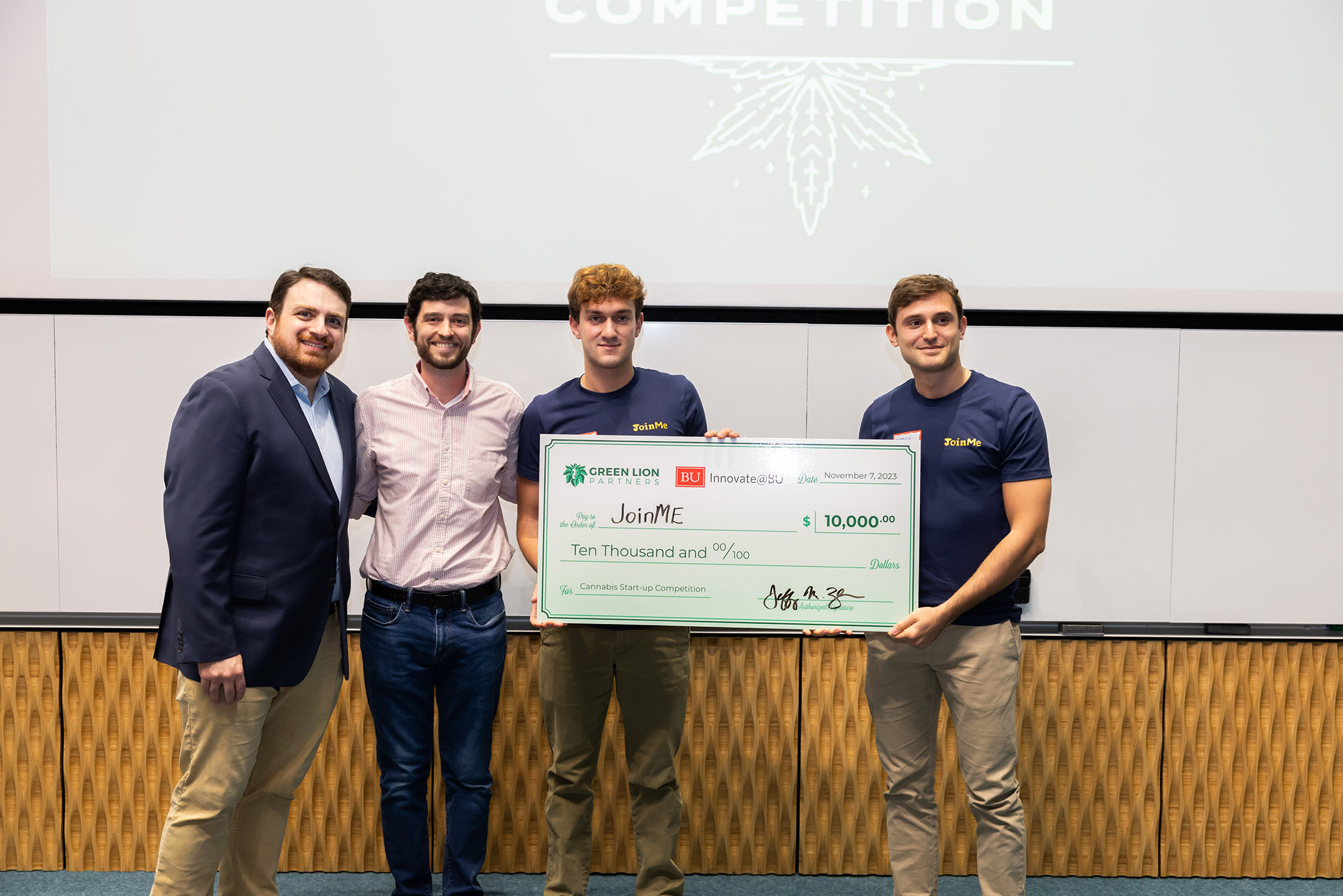 Photo: Four men pose for a photo, smiling for the camera. On the right, two men hold a giant cheque. their prize for winning the Cannabis Startup Competition.