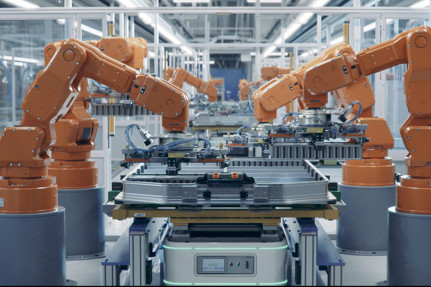 Photo: A set of 4 large orange robotic arms assembling a large electric car battery on a production line