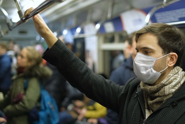 Photo: A man wearing a facemask on a busy subway train