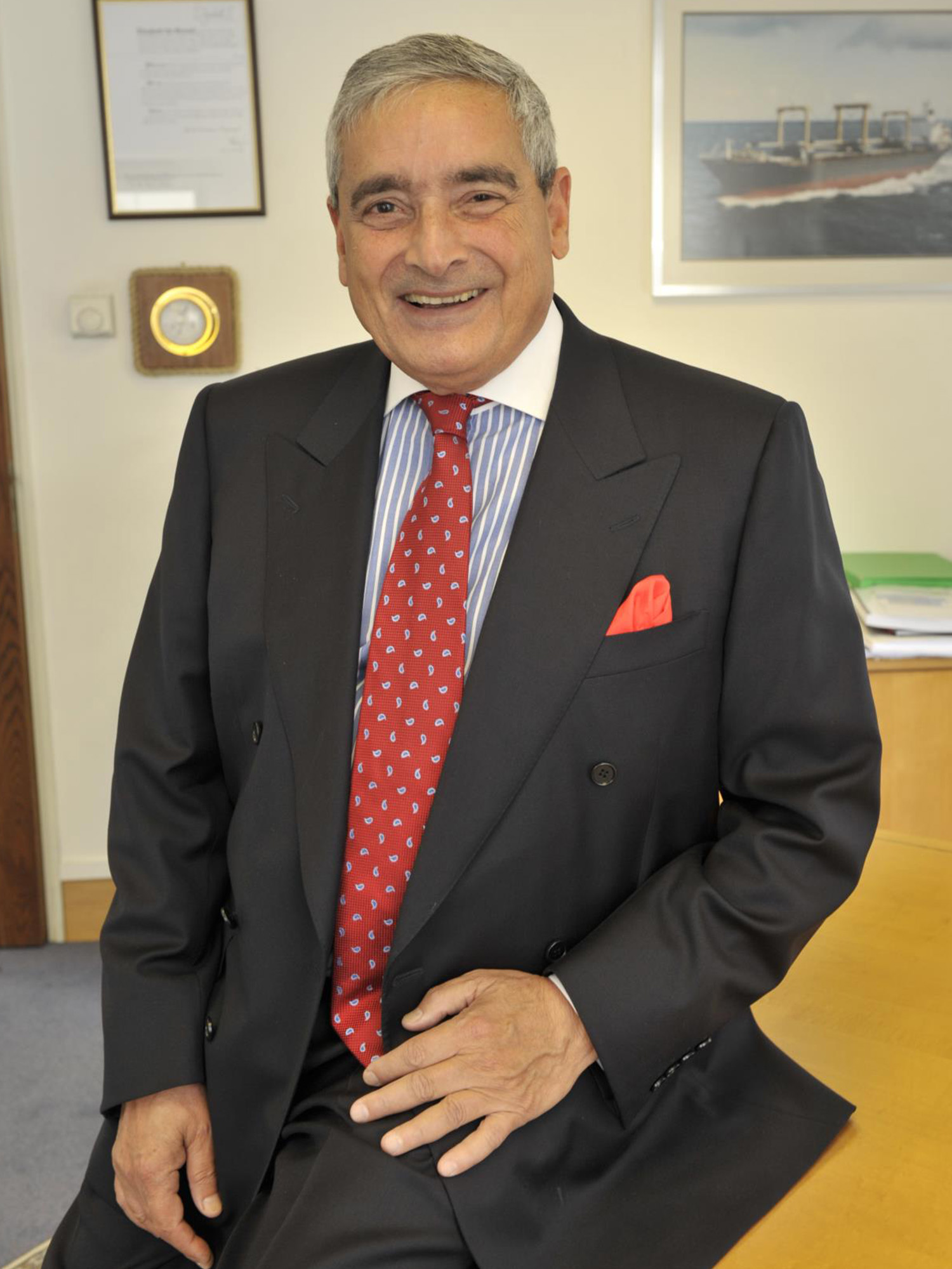 Photo: A man with a smile in a suit and tie in an office setting
