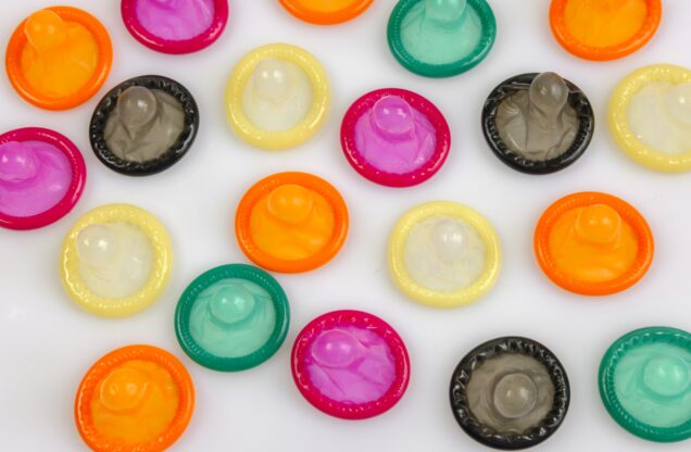 Photo courtesy of Canva. Colorful condoms laid out on a white surface