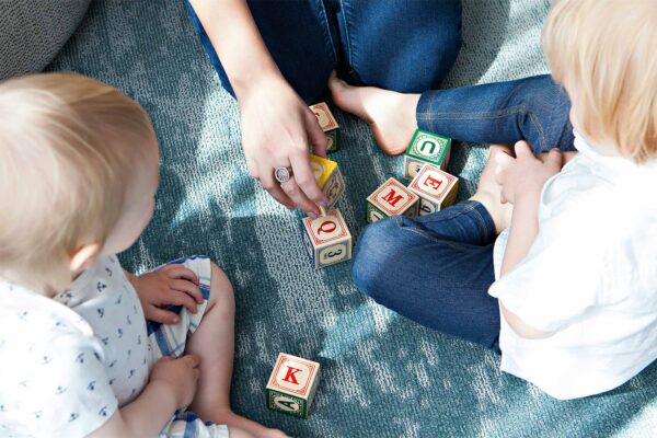 Photo: A family with two children playing with blocks with english letters on them