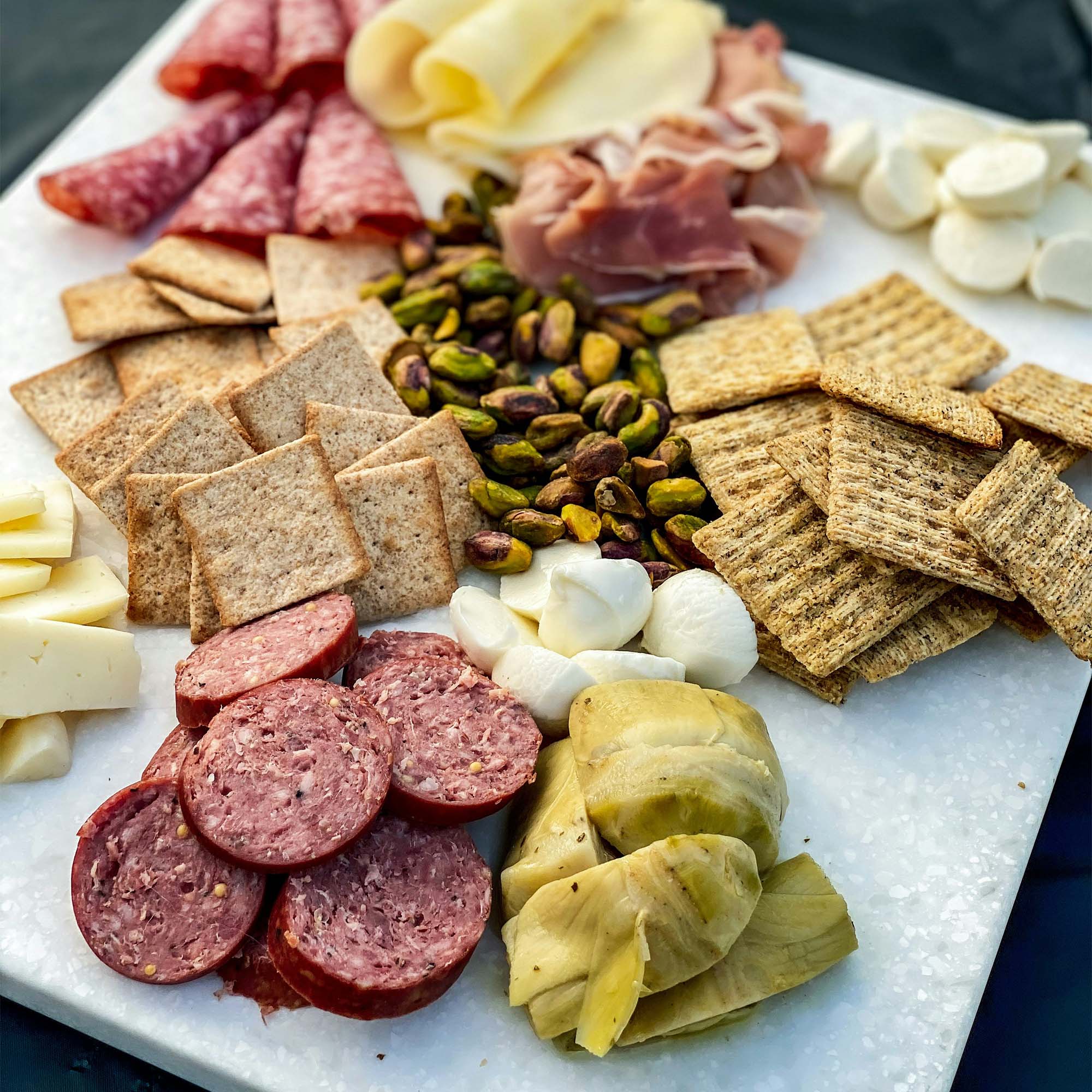 Photo: A full charcuterie board with meats, cheeses, and crackers on a stone plate