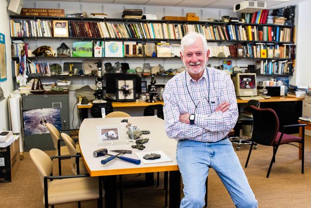 Photo: Wide shot of Lawford Anderson, a white man with white hair with his arms folded smiling for the photo. He wears a plaid shirt and light wash jeans.