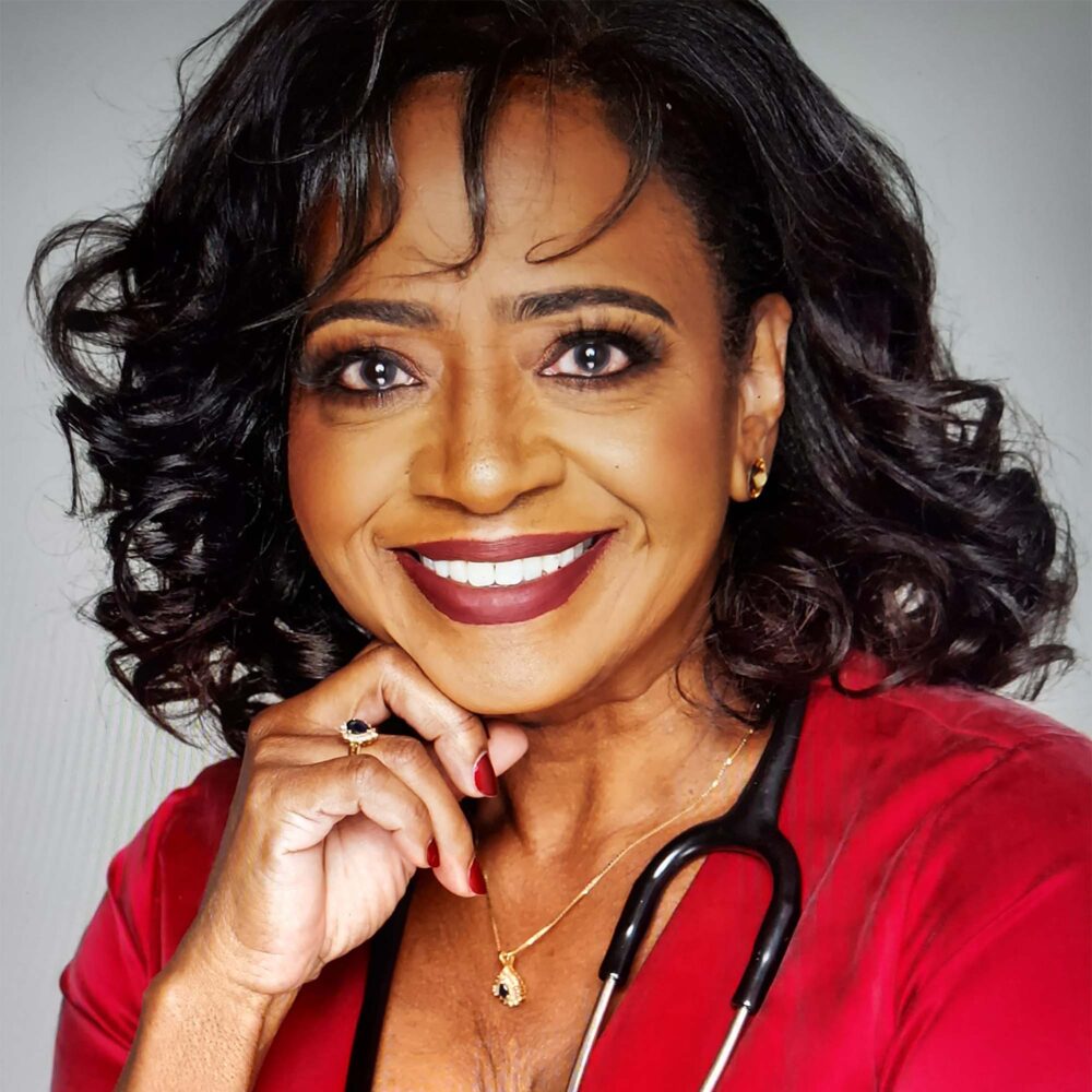 Photo: A black woman with dark flowing hair and a wide bright smiles in a portrait headshot