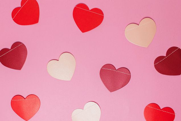 Photo: Paper cutouts of pink and red hearts on a pink paper background