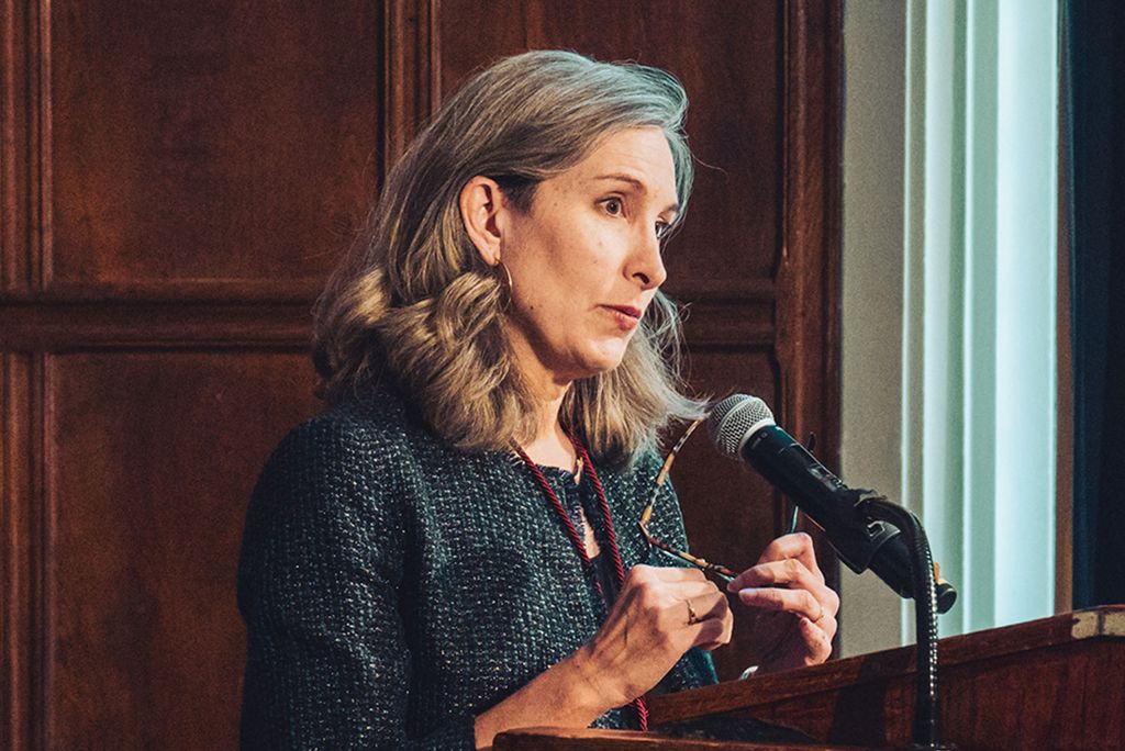 Photo: A woman with long gray hair stands at a podium and gives a speech