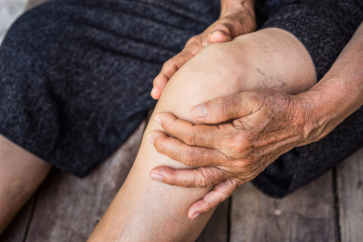 Photo: Stock photo of a individual holding their knee, seemingly in pain.