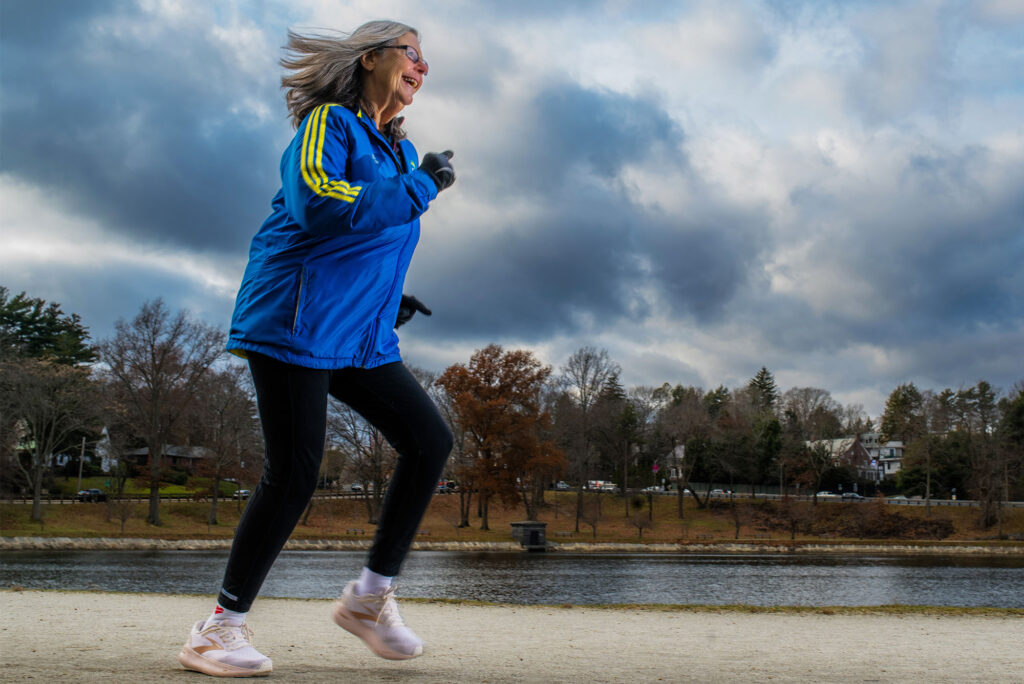 Photo: A woman wearing a blue jacket running around a large body of water