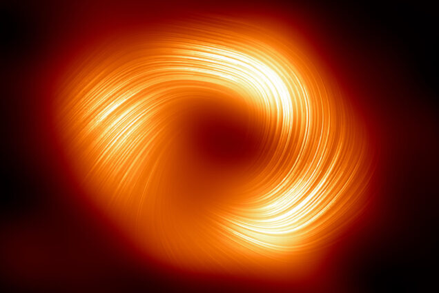 Photo: A new image of a supermassive black hole. There are orange swirls that are surrounded by darkness
