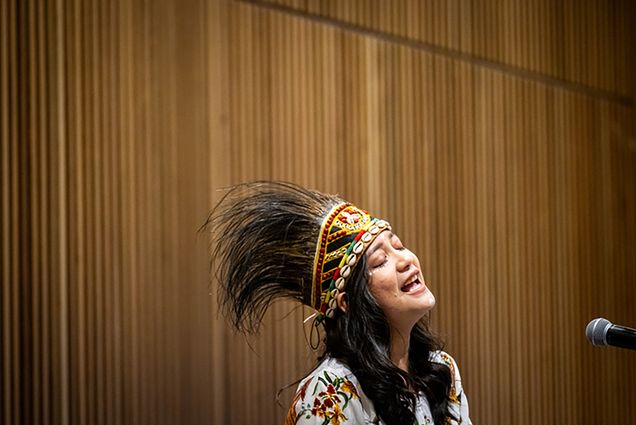 Photo: Sisilia Marpaung (CFA’25) sings a Biak song, followed by a Bahasa song of Indonesia while wearing a Papua crown during the Women of Color Circle's International Women's Day Celebration