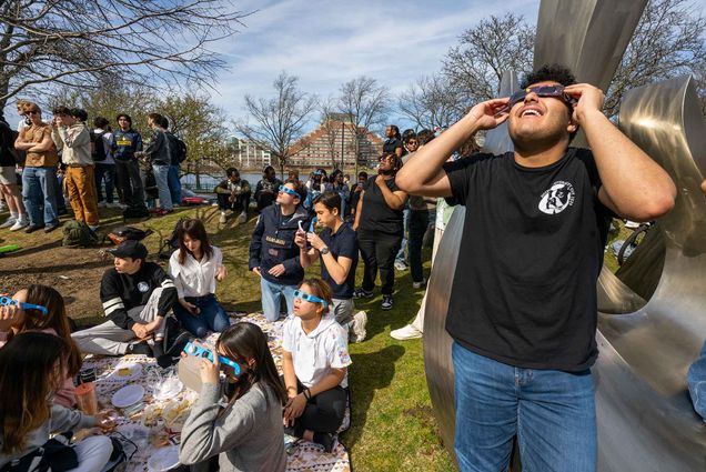 Photo: Surrounded by crowds with the same plan, Tawfiq Mukahall (Questrom’27) takes int he eclipse with a pair eclipse glasses on BU Beach