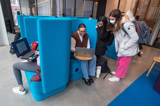 Photo: Becky Geisberg (CAS’26), center from left, Ella Hain (CAS’26), and Amelia Liston (CAS’26) chat for bit at SPARK on the second floor of the Center for Computing & Data Sciences. They sit on the computer in blue chairs and on their laptop.