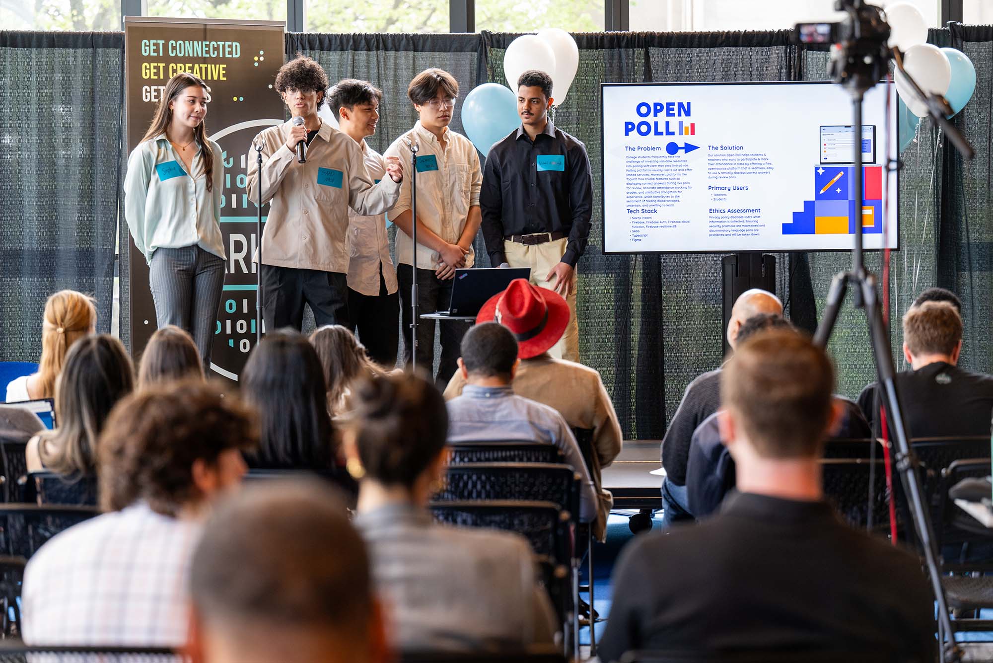 Photo: Students present their apps to judges, stakeholders, and visitors May 2 at CDS for BU Spark! Demo Day. They sand off to the side on the left, looking over the crowd in the foreground.