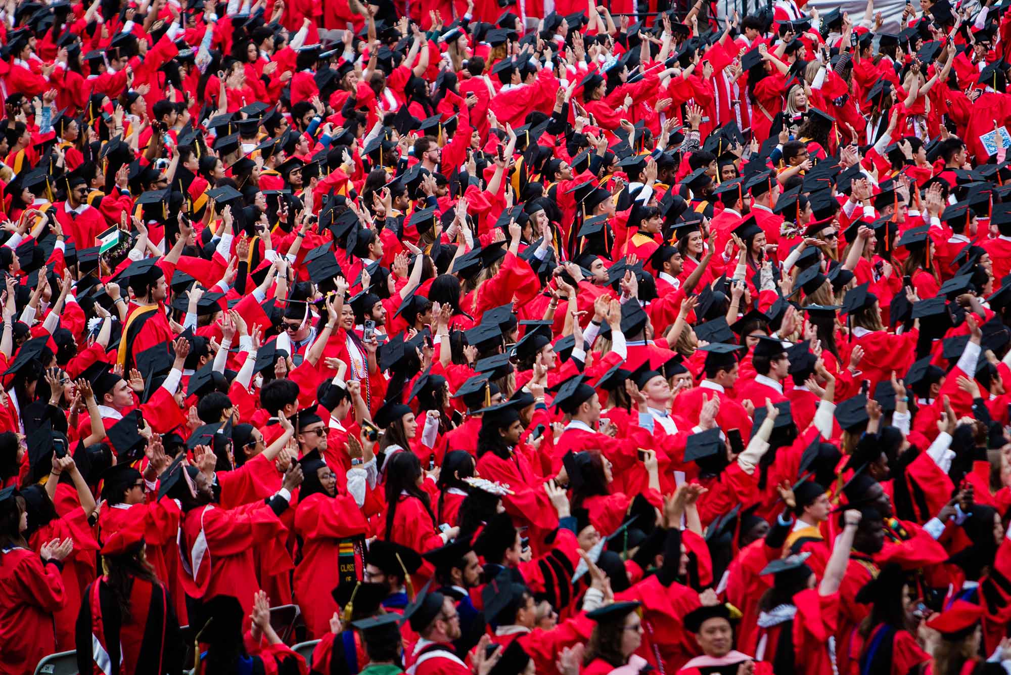 Photo: A sea of Boston University graduates in red gowns sit on Nickerson Field at the 151st Commencement in 2024