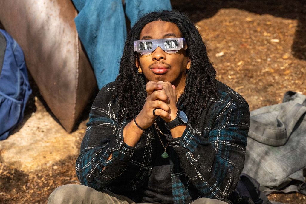Photo: A picture of a man in eclipse glasses looking up at the sky