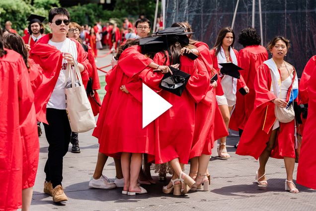 Photo: A picture of people in black graduation caps and red graduation gowns hugging in a crowd