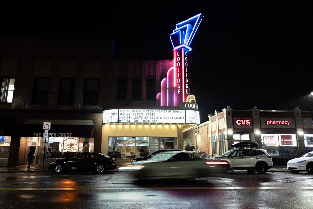 Photo: A picture of the Coolidge Corner Theatre at night with cars passing the road in front of it