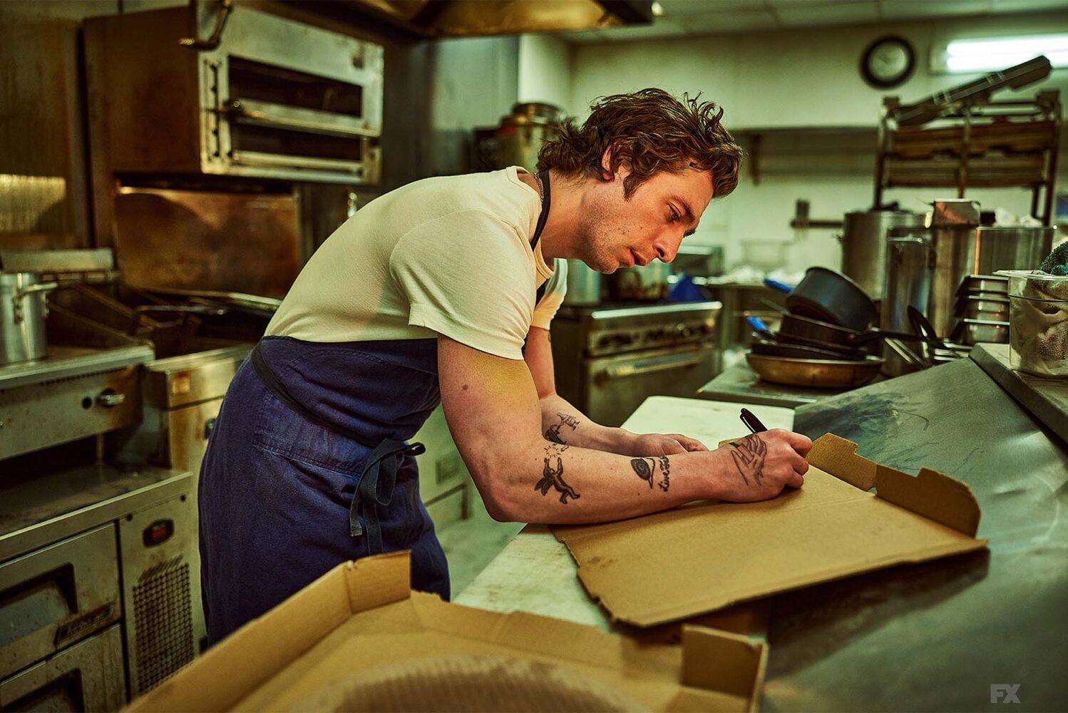 Photo still from FX's The Bear. A young male chef is seen labeling items in a kitchen setting