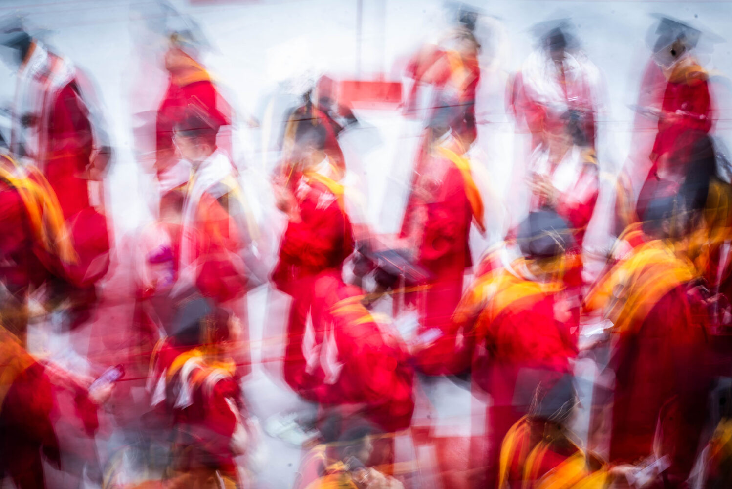 Photo: A stylistically blurry picture of many students in black graduation caps and red gowns