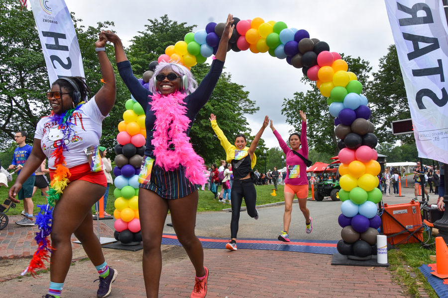 Photo: A picture of people completing a 5k by running under a vibrant, rainbow balloon arch