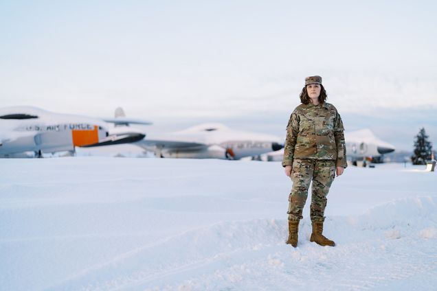 Photo: A white woman in a army uniform standing in the middle of nowhere in Alaska, snow covered as far as the eye can see.