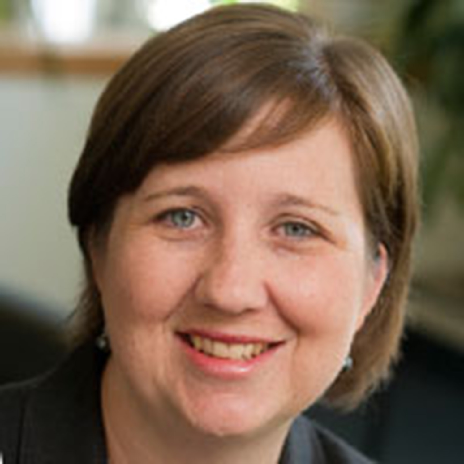 Photo: A headshot of a woman with short, brown hair smiling for the camera