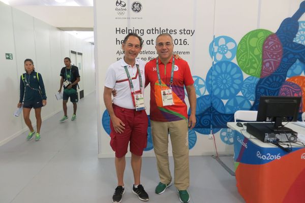 Photo: A picture of two men standing in front of a colorful wall at the Rio 2016 Olympics.