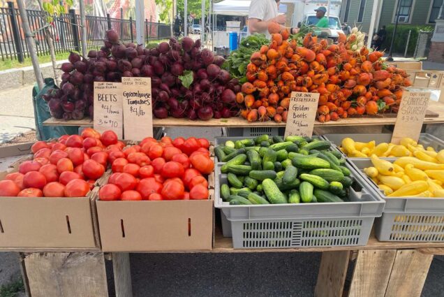 Photo: A picture of a farmer's market stand with tomatoes, cucumbers, squash, and beets