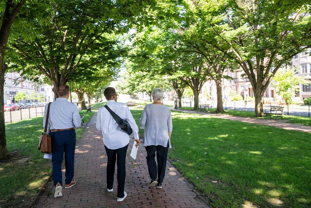 Photo: A group of people walking outside in a large sunny greenspace